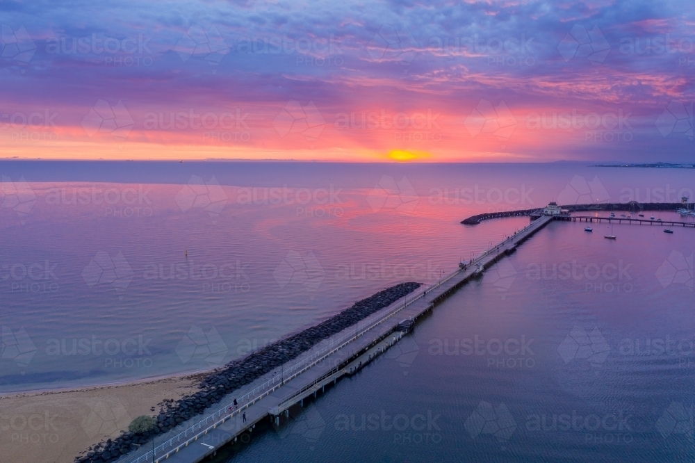 Aerial view of a dramatic purple sunset over a coastal jetty and breakwater - Australian Stock Image