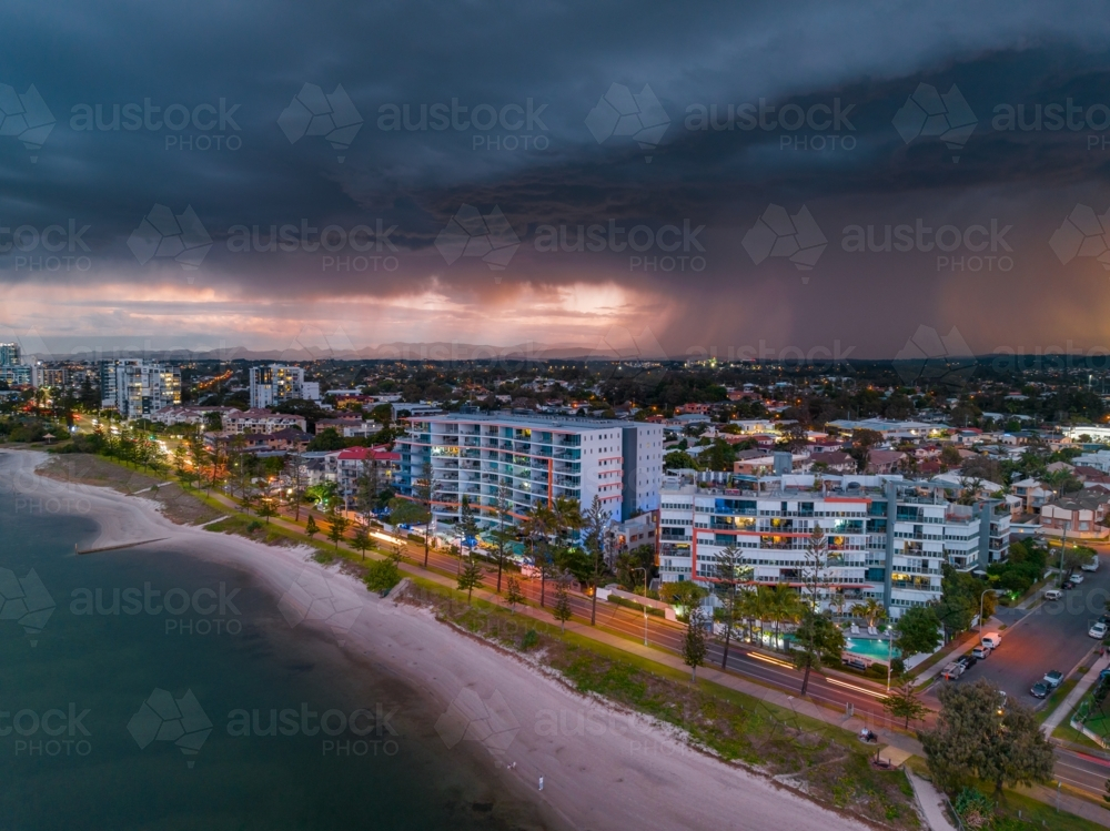 Aerial view of a dramatic thunderstorm advancing over apartment buildings along a coastal esplanade - Australian Stock Image