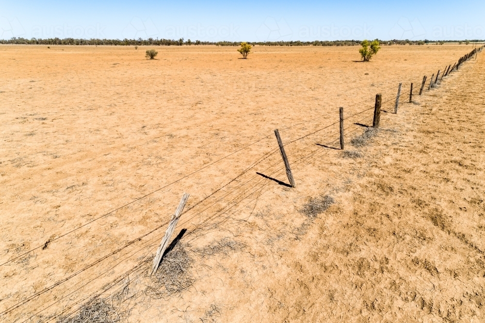 Aerial view of a fence and dusty paddock in drought affected Queensland. - Australian Stock Image