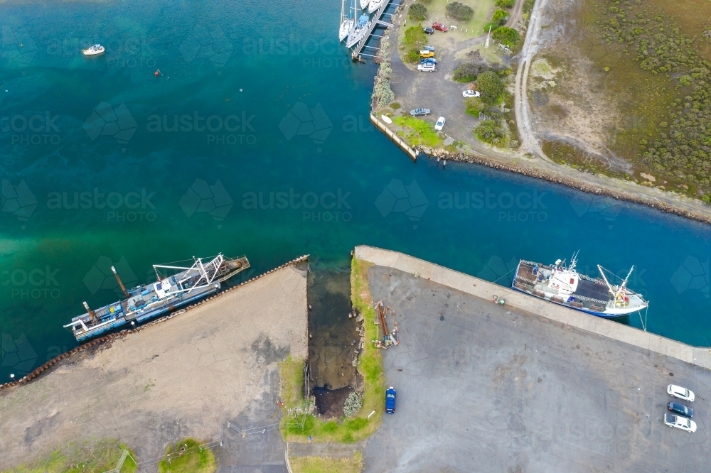 Aerial view of a fishing boat and a dredge docked in a coastal channel - Australian Stock Image