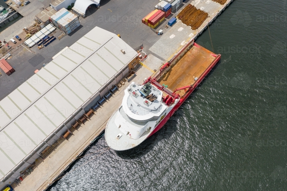 Aerial view of a fishing trawler sitting beside a warehouse on a dock. - Australian Stock Image