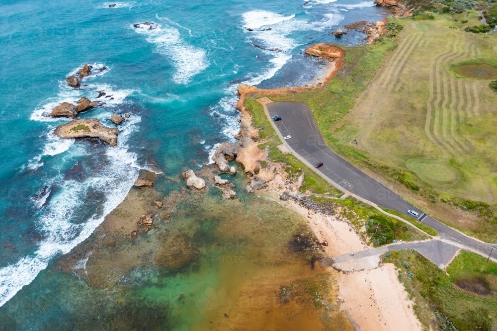 Aerial view of a golf course and carpark along side a rugged coastline - Australian Stock Image