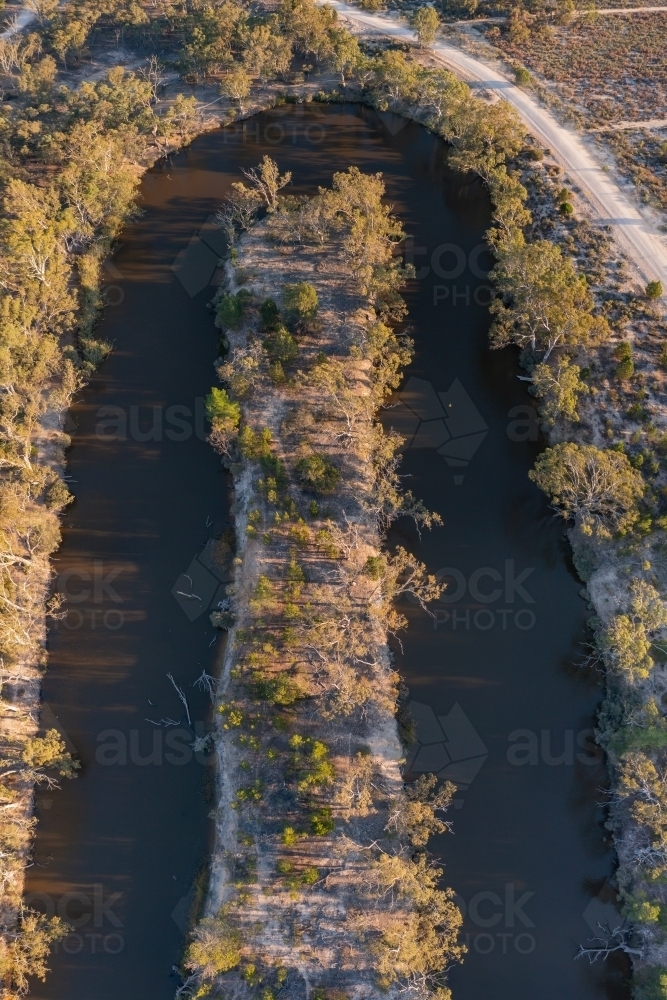 Aerial view of a hairpin bend in a murky river lined with gumtrees - Australian Stock Image