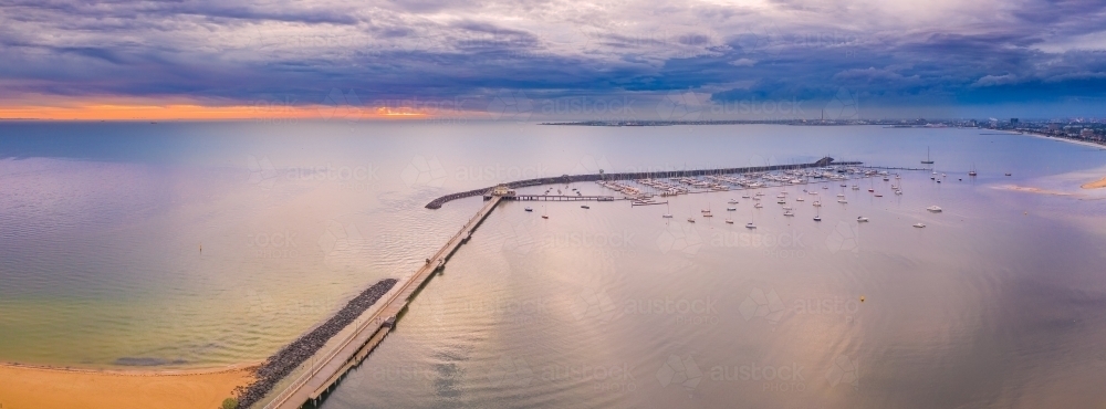 Aerial view of a jetty and breakwater on a calm bay at sunset - Australian Stock Image
