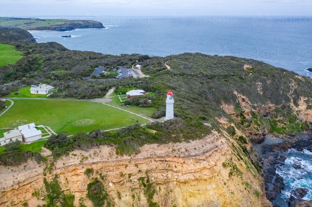 Aerial view of a lighthouse perched on a clifftop above a rugged coastline - Australian Stock Image