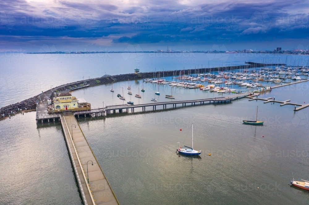 Aerial view of a long narrow jetty over a calm bay under a dark twilight sky - Australian Stock Image