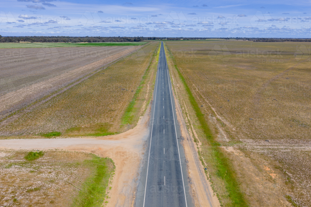 Aerial view of a long straight country through barren rural land - Australian Stock Image