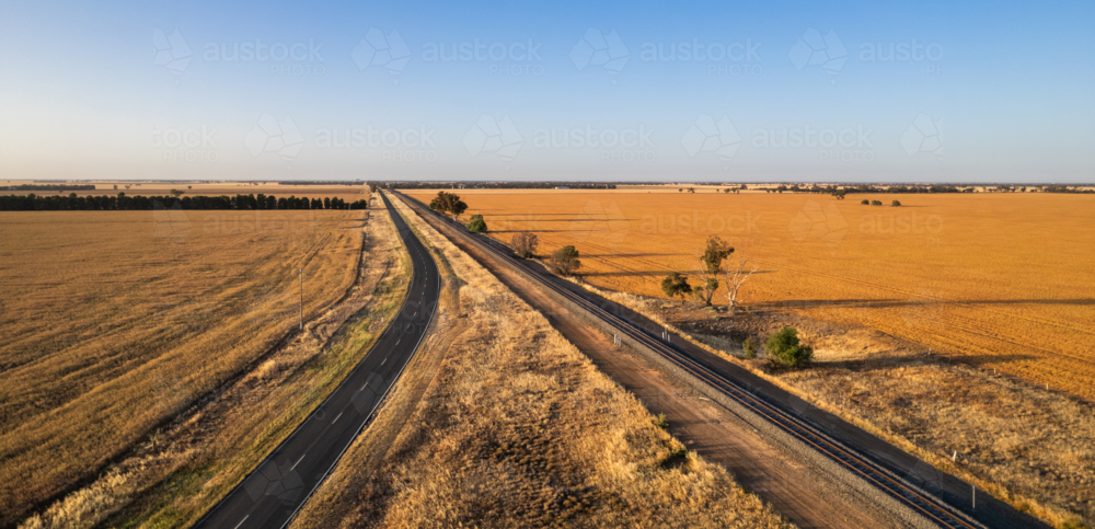 Aerial view of a long, straight road in a vast farmland - Australian Stock Image