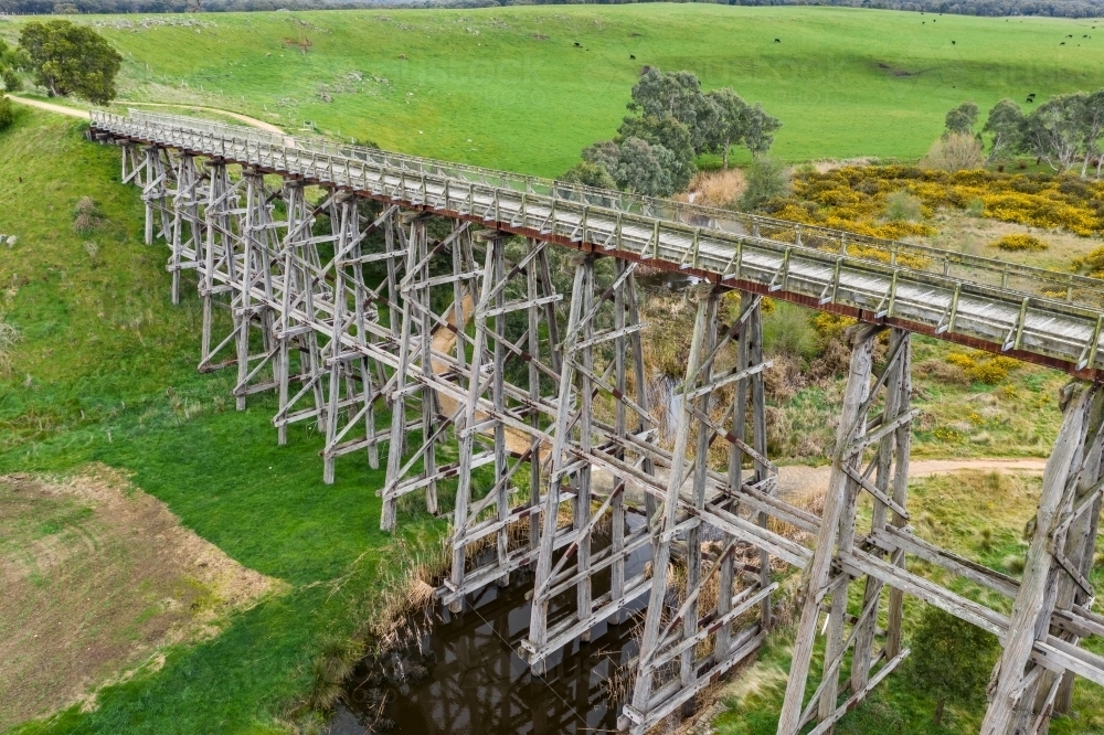 Timber Bridge Large Image of Aerial view of a long wooden trestle bridge across a green ...