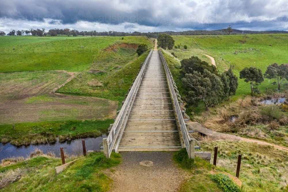 Aerial view of a long wooden trestle bridge across a green valley - Australian Stock Image