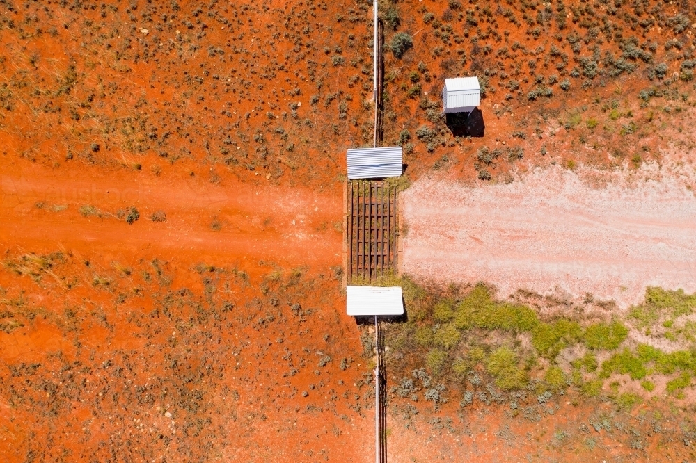 Aerial view of a mailbox and cattle grate in a dirt track across red barren land - Australian Stock Image