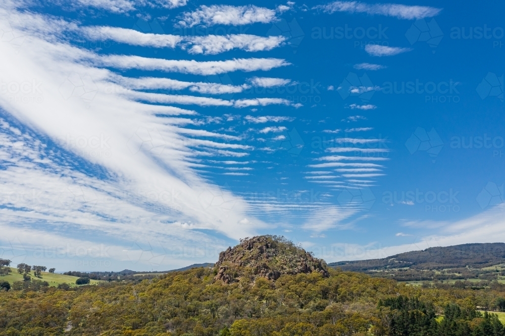 Aerial view of a mountainous rock formation with an unusual cloud formation above - Australian Stock Image