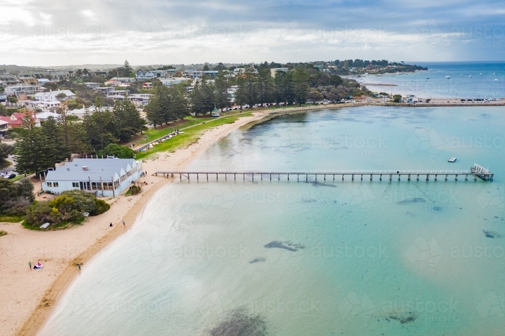Aerial view of a narrow fishing jetty from a beach out over shallow water - Australian Stock Image