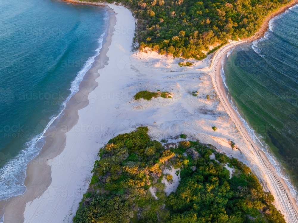 Aerial view of a narrow sand spit with forest on either side - Australian Stock Image