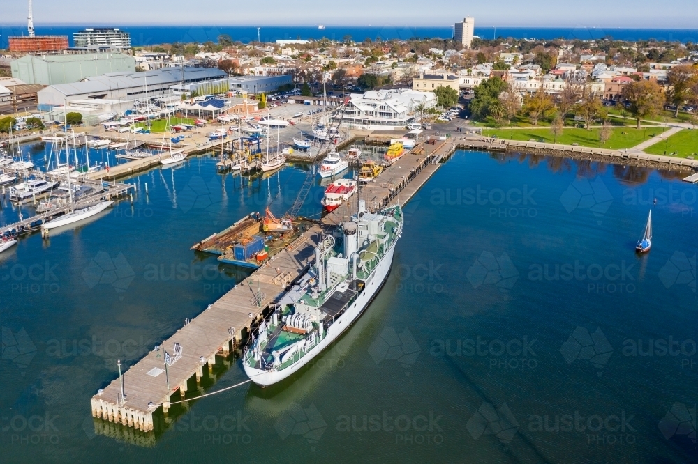 Aerial view of a naval ship at a dock at a bay side harbour - Australian Stock Image