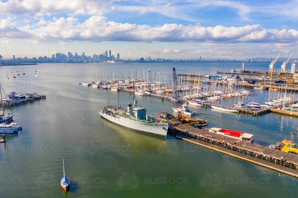 Aerial view of a naval ship at a dock at a bay side harbour - Australian Stock Image