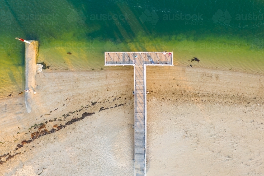 Aerial view of a people fishing on a T shaped jetty at the coast - Australian Stock Image