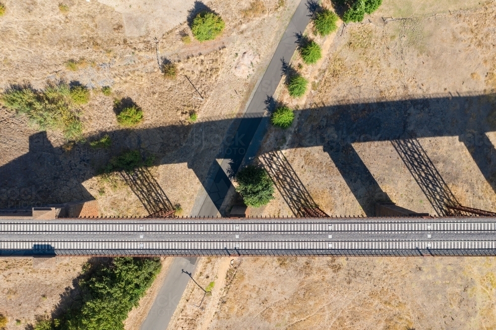 Aerial view of a railway viaduct and its shadow above a country road - Australian Stock Image