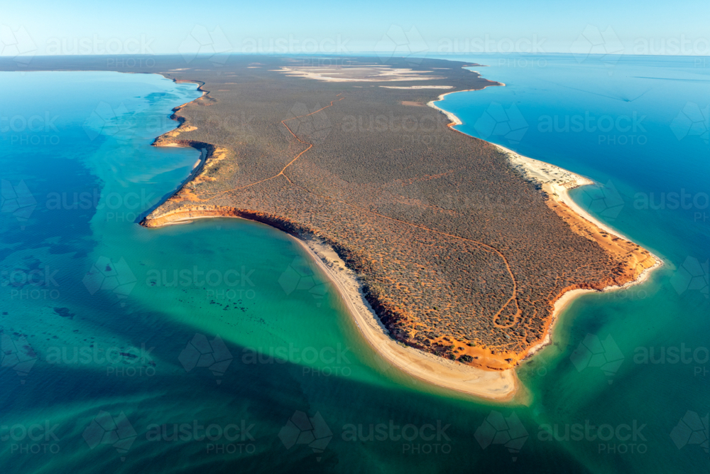Aerial view of a remote bush-covered peninsula surrounded by turquoise and blue ocean waters - Australian Stock Image