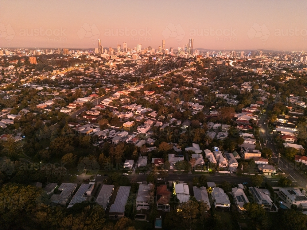 Aerial view of a residential area under the sunset sky with city skyline at the edge - Australian Stock Image