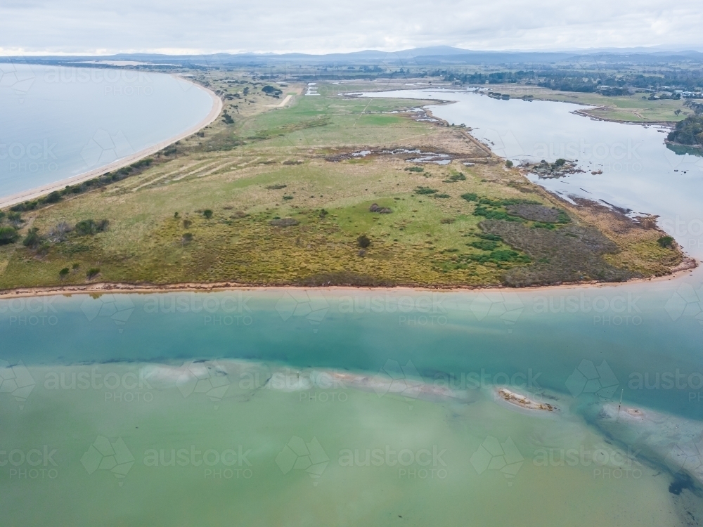Aerial view of a river flowing around a peninsula from a coastal lagoon - Australian Stock Image
