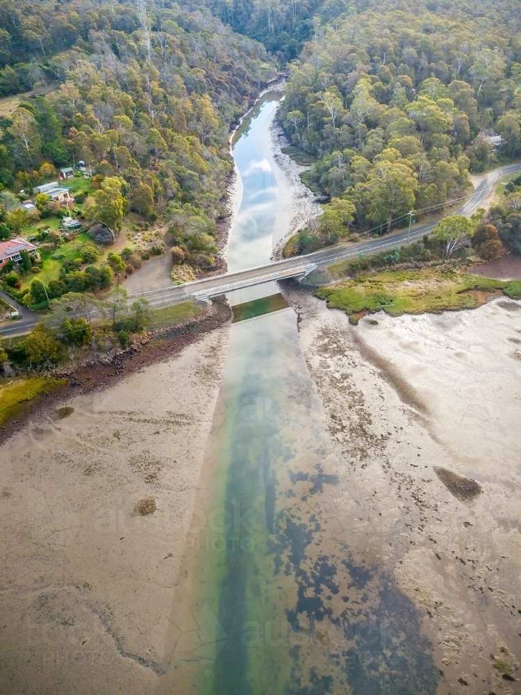 Aerial view of a river flowing down a valley and under a bridge - Australian Stock Image
