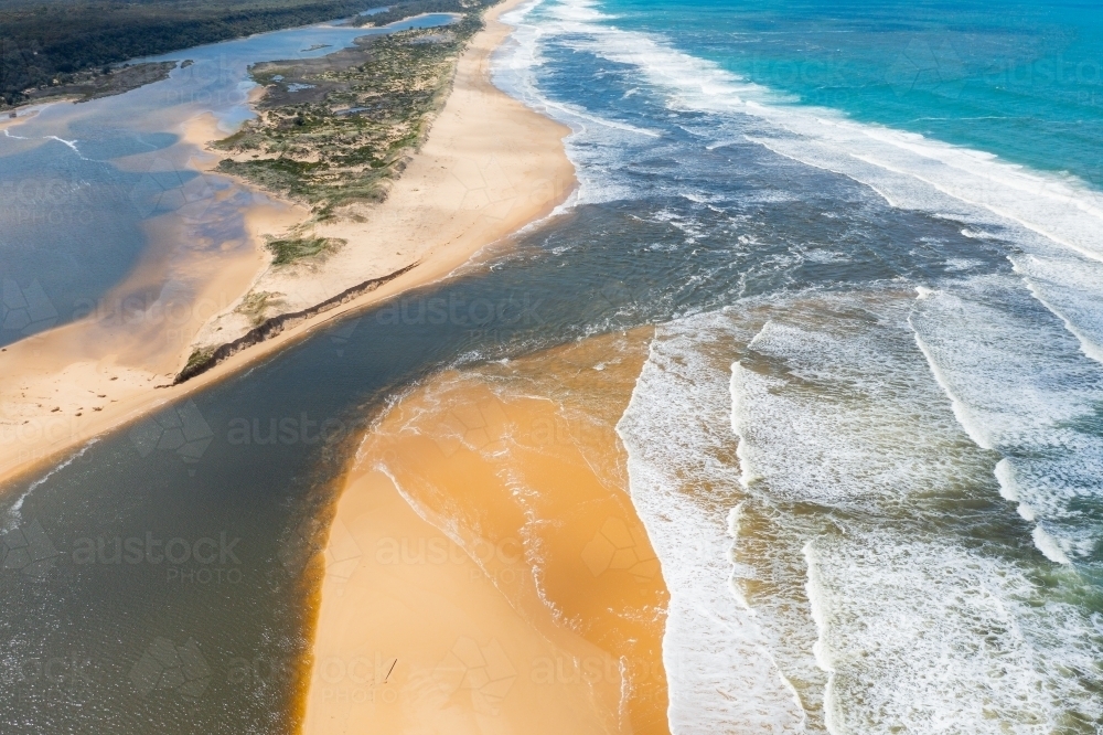 Image of Aerial view of a river flowing out to sea through a sandy ...