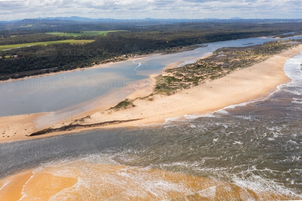 Image of Aerial view of a river flowing out to sea through a sandy ...