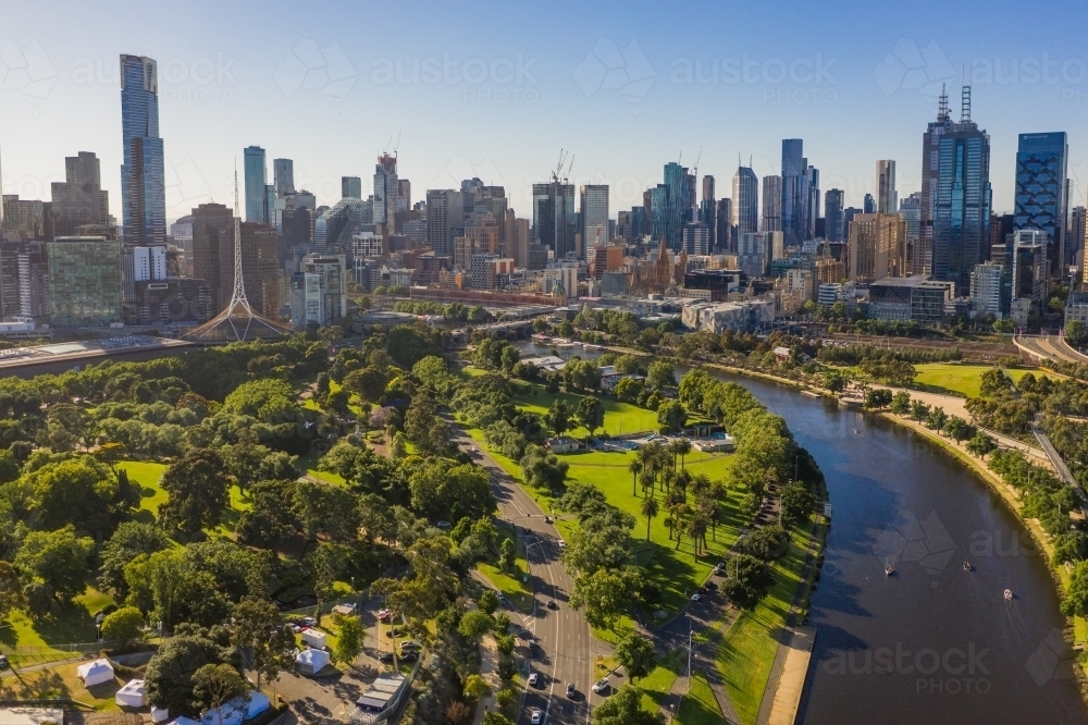 Aerial View of a river flowing through parkland toward a city skyline - Australian Stock Image