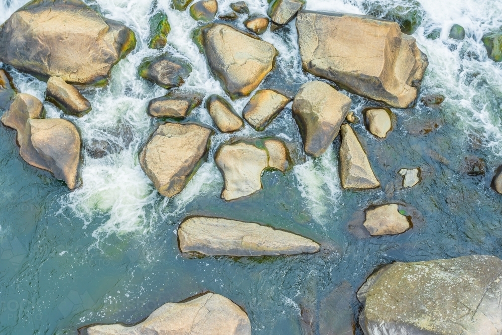 Image of Aerial view of a river running around large rocks - Austockphoto