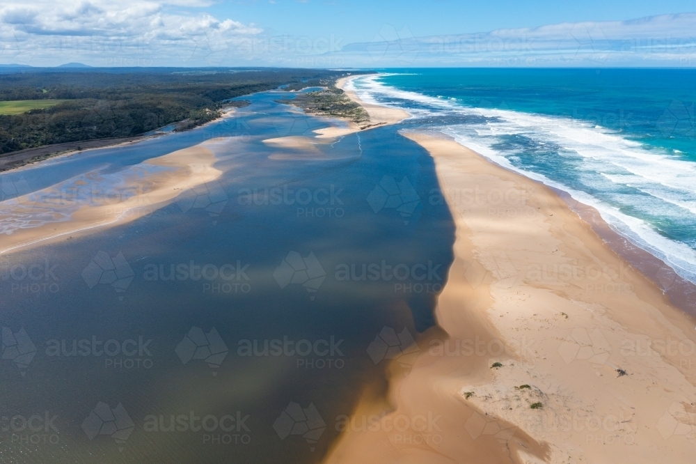 Image of Aerial view of a river running next to a sandy beach then out ...