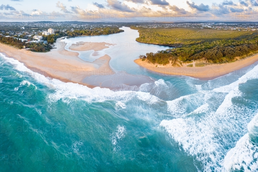 Aerial view of a river winding out to sea over a sandy beach - Australian Stock Image