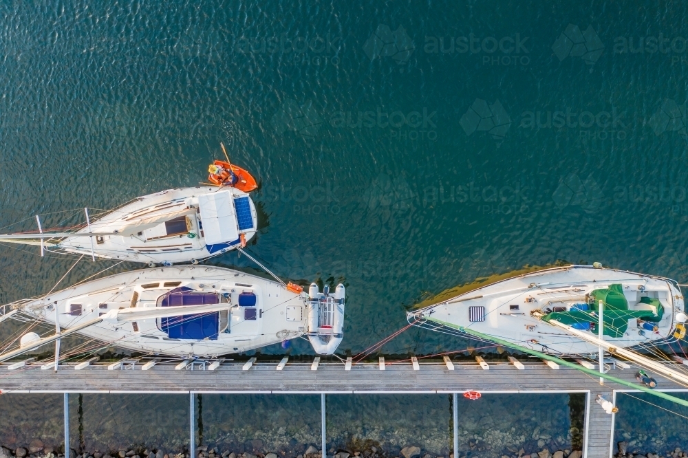 Aerial view of a row boat and yachts moored at a jetty - Australian Stock Image