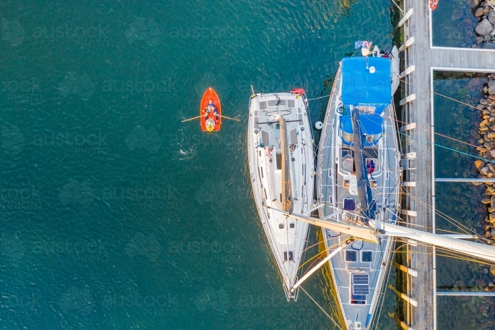 Aerial view of a row boat and yachts moored in a marina - Australian Stock Image