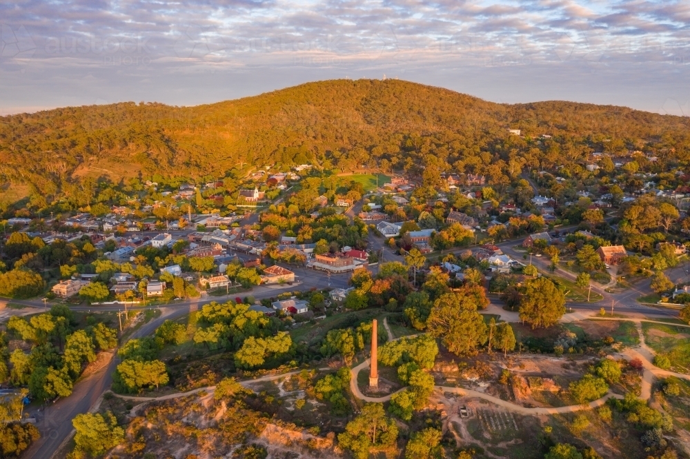 Aerial view of a rural town and mountain backdrop in early morning lighting - Australian Stock Image