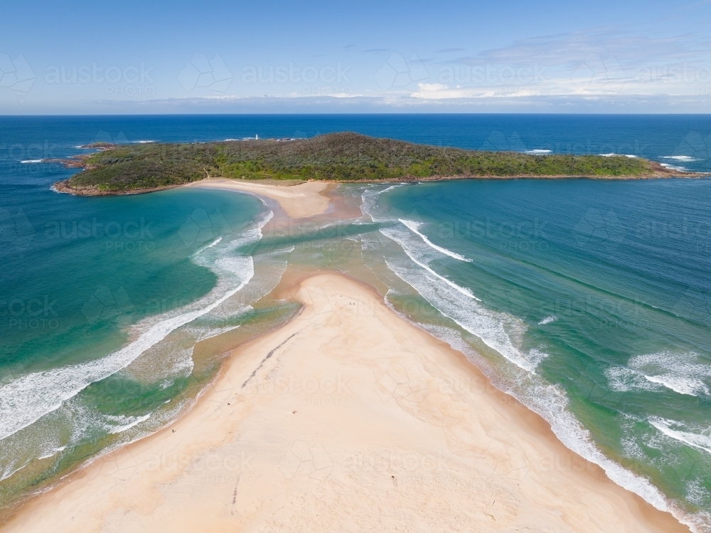 Aerial view of a sand spit leading out to a forested coastal island - Australian Stock Image