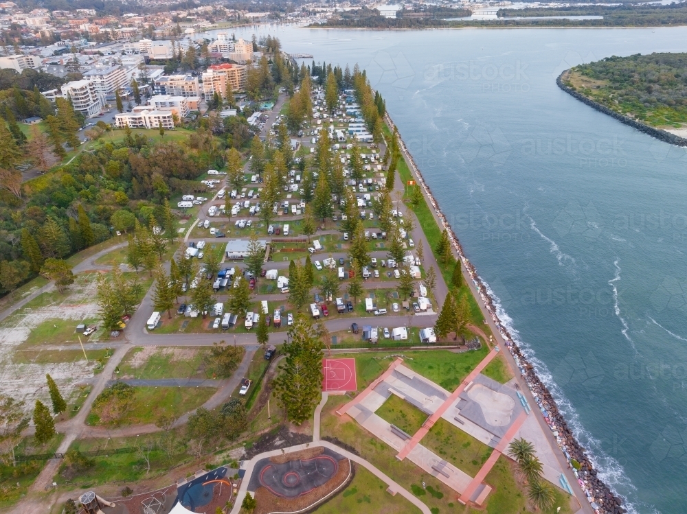 Aerial view of a skate park and caravan park on the banks of a wide river - Australian Stock Image