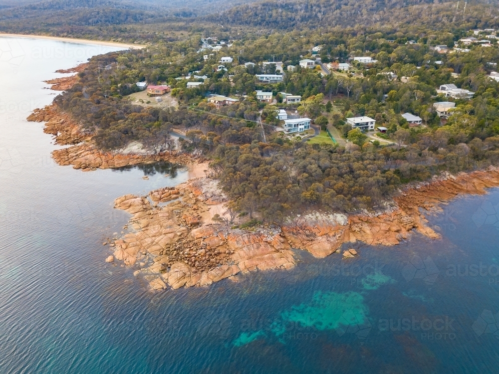Aerial view of a small coastal town behind a rocky shoreline - Australian Stock Image