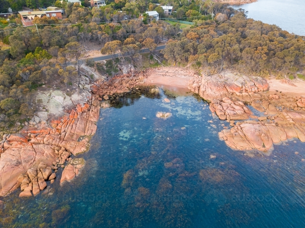 Aerial view of a small coastal town behind a rocky shoreline - Australian Stock Image