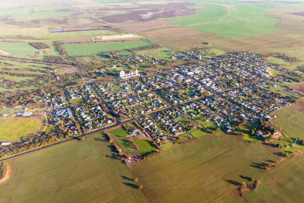 Aerial view of a small rural town surrounded by green farmland and open plains - Australian Stock Image