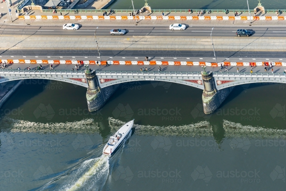 Aerial view of a speedboat about to go under a bridge over a river - Australian Stock Image