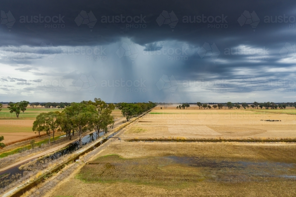 Aerial view of a storm cloud dropping rain on dry farmland - Australian Stock Image