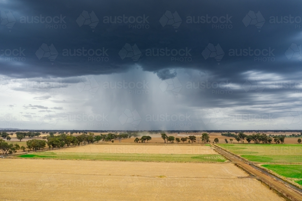 Aerial view of a storm cloud dropping rain on dry farmland - Australian Stock Image
