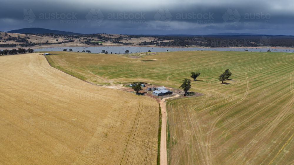 Aerial view of a straight country road leading to a group of farm sheds amid dry paddocks - Australian Stock Image