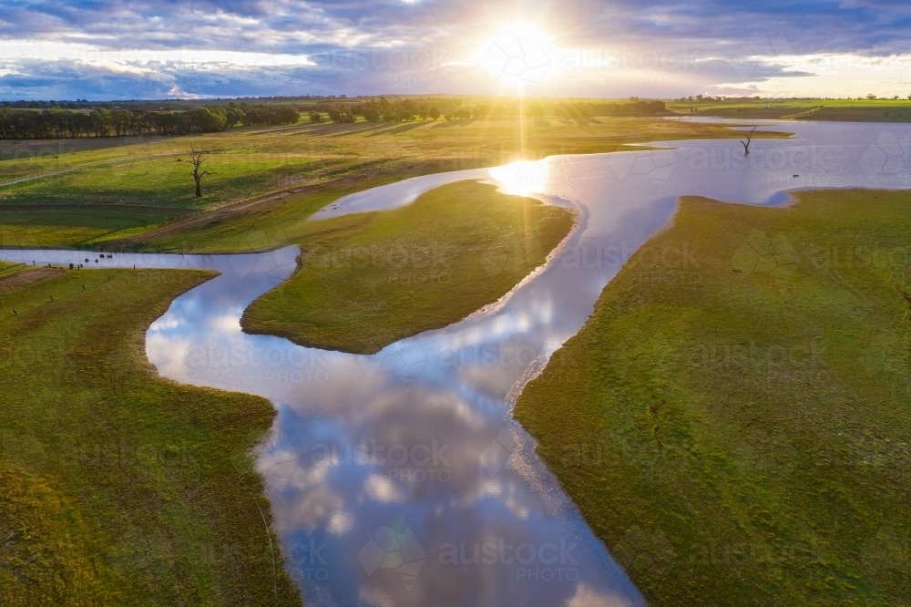 Aerial view of a sunset over a river flowing around a small island - Australian Stock Image