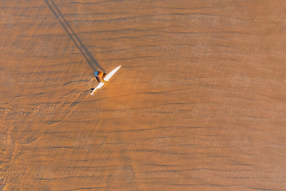 Image of Aerial view of a surfer carrying his board on the beach ...