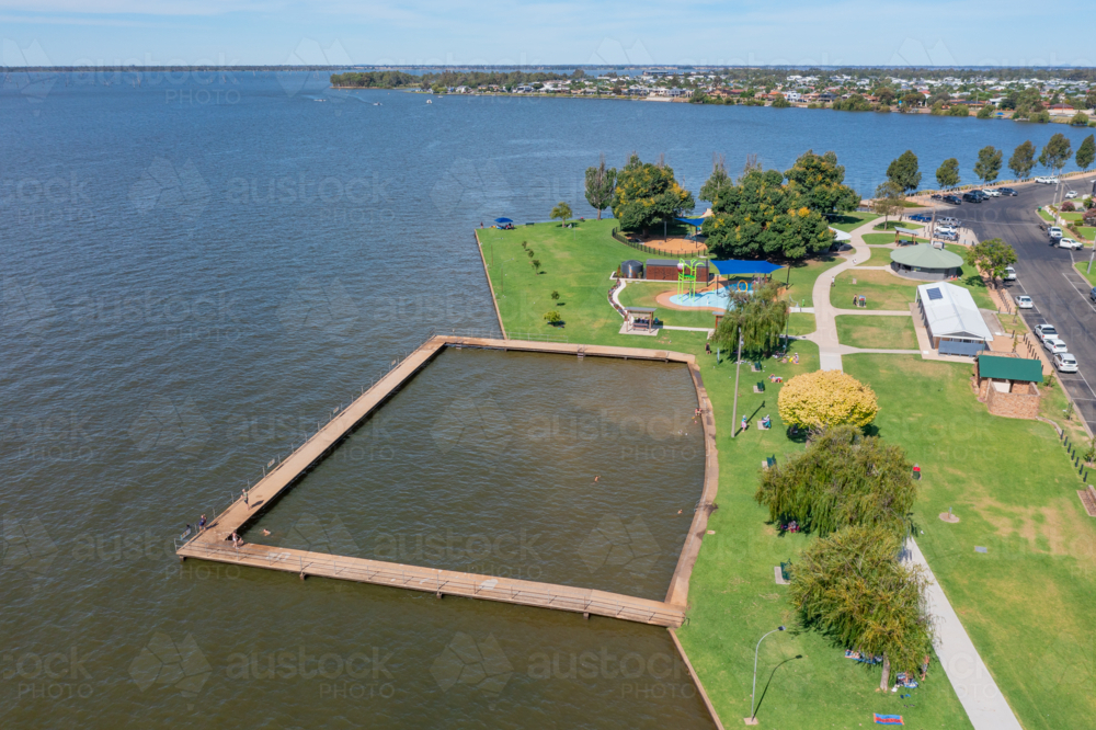 Aerial view of a swimming enclosure and playground on the shore of a town lake - Australian Stock Image