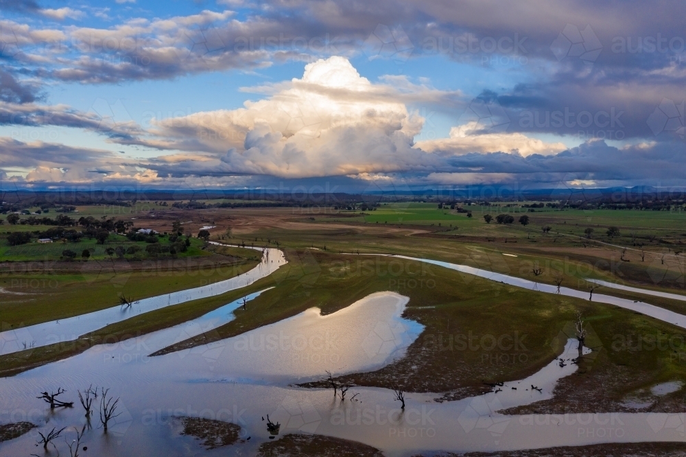 Aerial view of a system of narrow rivers winding into the distance under a dramatic cloudy sky - Australian Stock Image