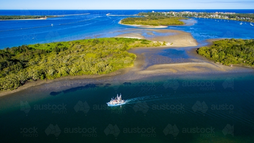 Aerial view of a trawler departing Yamba on the Clarence River - Australian Stock Image