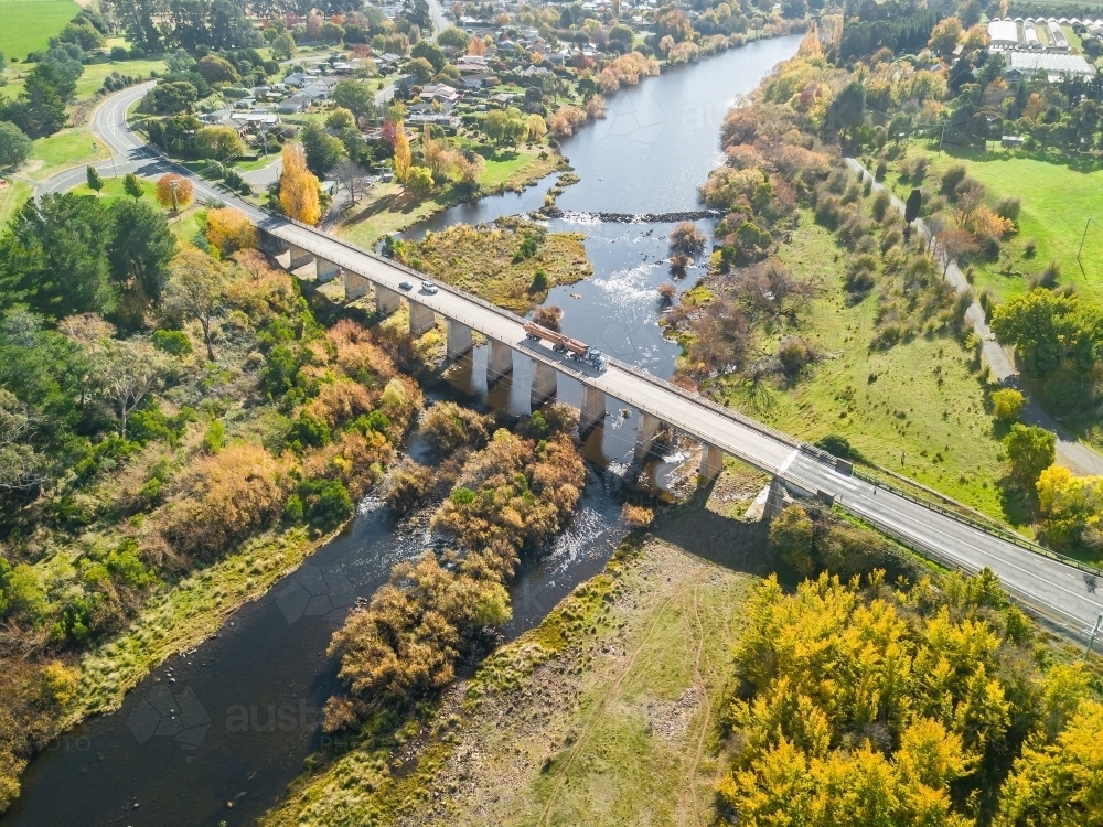Aerial view of a truck crossing a bridge leading into a riverside country town - Australian Stock Image